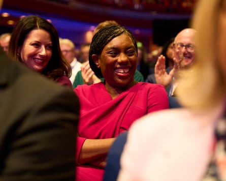 Badenoch smiles in the audience of Andrew Griffith’s speech at the conference