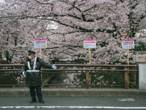 A private guard asks people to not stop on a bridge to enjoy the cherry blossoms
