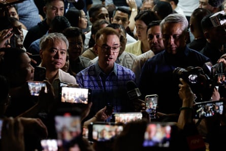 Alan Peter Cayetano speaks to media from the centre of a crowd with cameras and phones held in front of him.