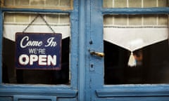 Blue-painted doorframe with white lace curtains and a blue-and-white sign that says 'Come In, We're Open'