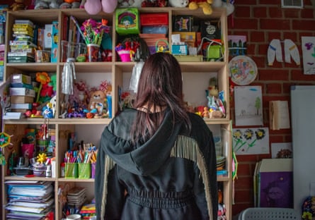 Sonya seen from behind standing in front of bookshelves full of toys and papers