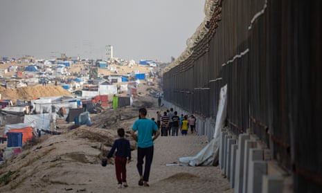 Displaced Palestinians walk next to the border fence with Egypt in Rafah, in the southern Gaza Strip.