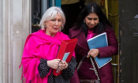 Nadine Dorries in a fuchsia pashmina and Nadine Dorries in a magenta jacket, both holding documents, emerge from a doorway