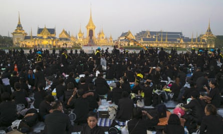 Thai mourners sit in front of the royal crematorium and funeral complex.