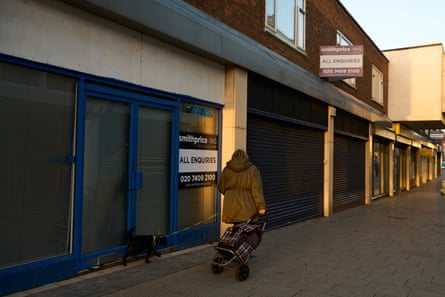 A person walks their dog along a row of closed shops