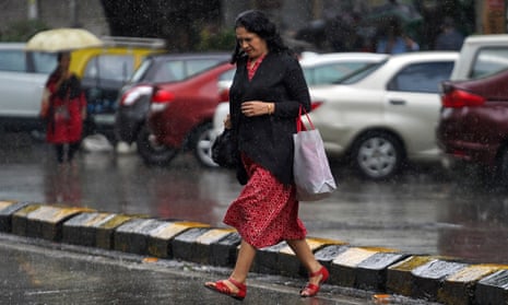 A woman crosses a road as it rains in Mumbai, India,