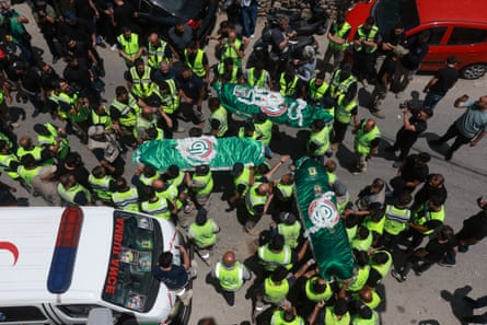 Aerial view of people in hi-vis vests surrounding the flag-draped bodies of three people