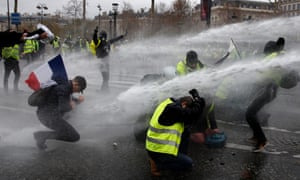 Gilets jaunes are sprayed with water cannon near the Arc de Triomphe. Photograph: Yoan Valat/EPA