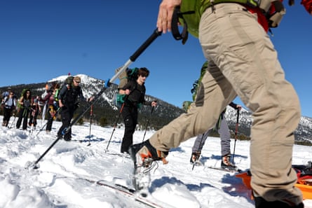 A group of people wearing cross country skis set out on a trip.