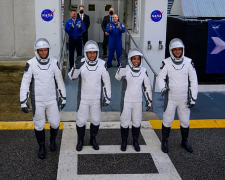 Line of four astronauts in white spacesuits and helmets.