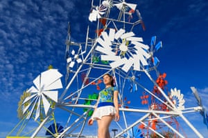 A woman poses in front of a towering art installation