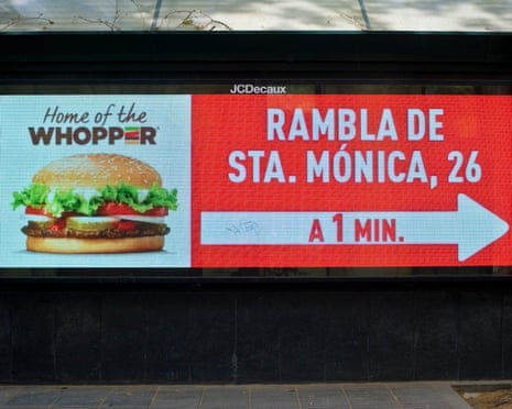 A digital billboard advertises Burger King's Whopper with text directing to Rambla de Sta. Mónica, 1 minute away