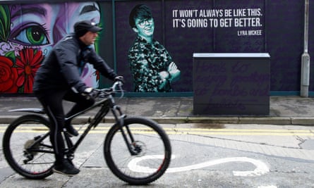 A man cycles past a mural featuring Lyra McKee in Belfast.