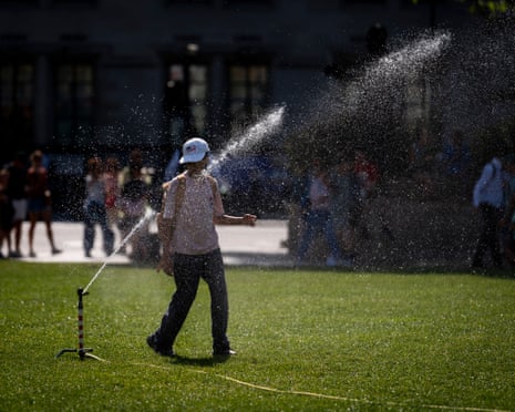 A person plays with a water sprinkler at Parliament Square in central London