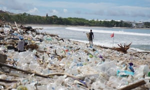 Um surfista está diante de montes de lixo na famosa Praia de Kuta em Bali