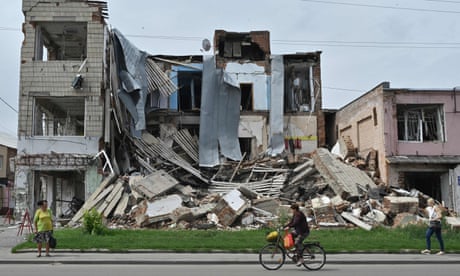 Pedestrians walk past a destroyed store in the city of Okhtyrka.