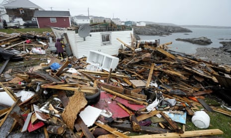 A person standing amid wreckage from a wooden home on the seashore destroyed by a storm