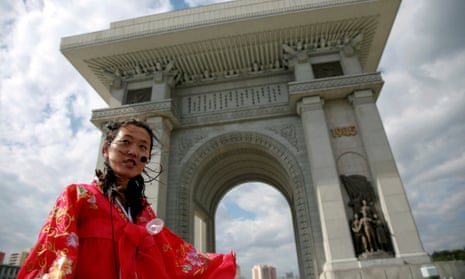 A guide wearing a traditional dress speaks to visitors at the Arch of Triumph in Pyongyang.