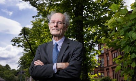 Prof Sir John Curtice: he is pictured standing in a leafy Glasgow street with a large tree and a stone building behind him; he is standing with his arms folded. He is 70 years old, tall and thin, and is mostly bald with grey hair blowing in the wind either side of his head; he wears glasses, a dark grey suit, white shirt and tie.