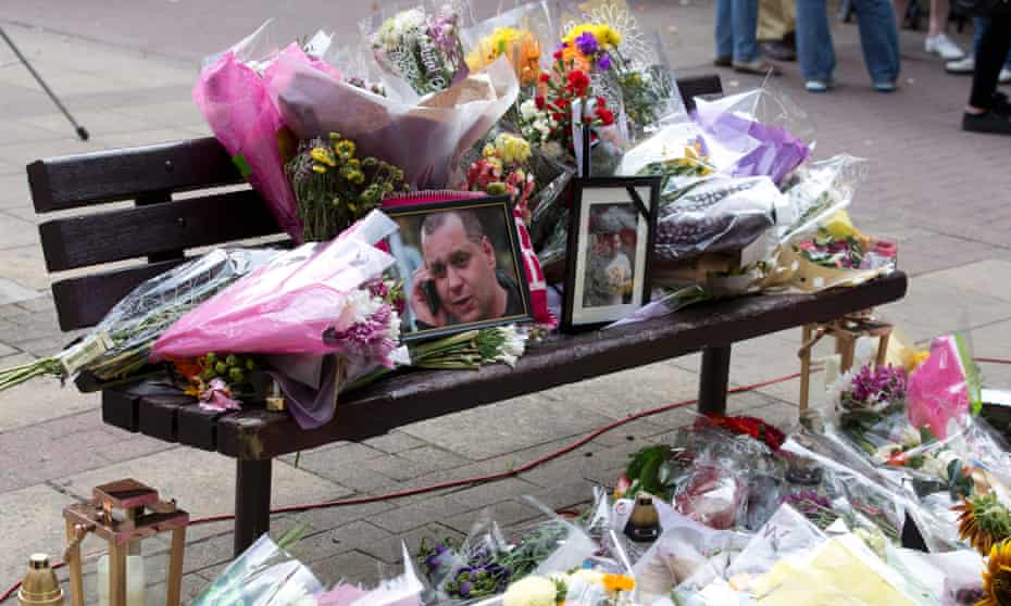 Floral tributes and a photograph of Arkadiusz Jóźwik are seen on a bench in Harlow, Essex