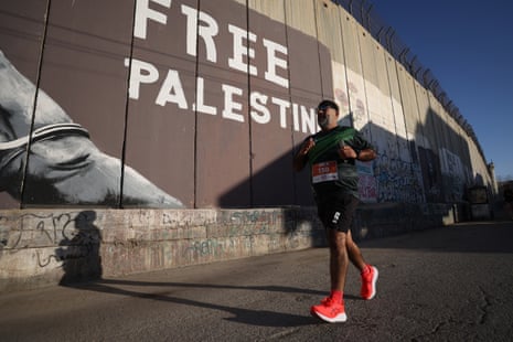 A man runs past a wall with the message "Free Palestine".