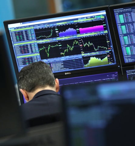 En trader jobber mens skjermer viser markedsdata i London, Storbritannia