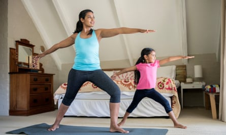 A mother and daughter practise yoga in a bedroom together