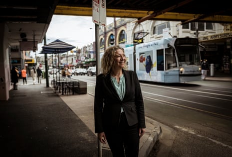 Melissa Lowe is standing on a footpath in Melbourne as a tram moves past