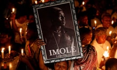 A woman holds a photograph of the late Nigerian singer MohBad, during a candlelight procession in Abuja on 22 September.