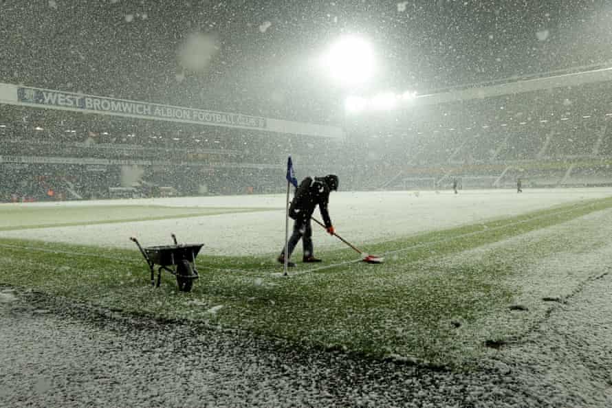 Heavy snow falls before the game between West Bromwich Albion and Arsenal at the Hawthorns as a groundsman try to clear the lines.