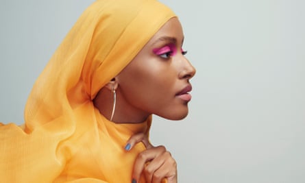 Shahira Yusuf, face in profile, heavy pink eyeshadow, a yellow/orange scarf around her head and neck