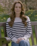 The Princess of Wales, in a striped Breton sweater and jeans and with long wavy hair, sits on a garden bench with her legs crossed and hands folded on her knee