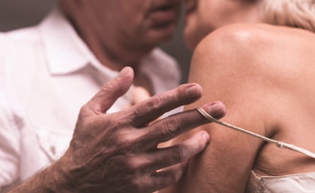 An older couple embrace, with the man slipping the strap of a camisole from his partner’s shoulder