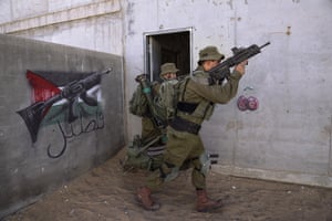 Soldiers carry ammunition past a graffiti featuring the Palestinian flag