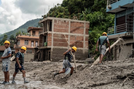 Emergency workers search through the mud