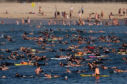 Surfers and swimmers paddle and swim out at Bondi beach.