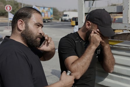 Sadi rubs his eyes while another man speaks on a phone