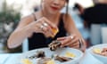 Close-up of woman's hand squeezing lemon juice on fresh oysters<br>Mid-section of young woman eating oyster at outdoor restaurant. Luxury lifestyle. Food and travel concepts.