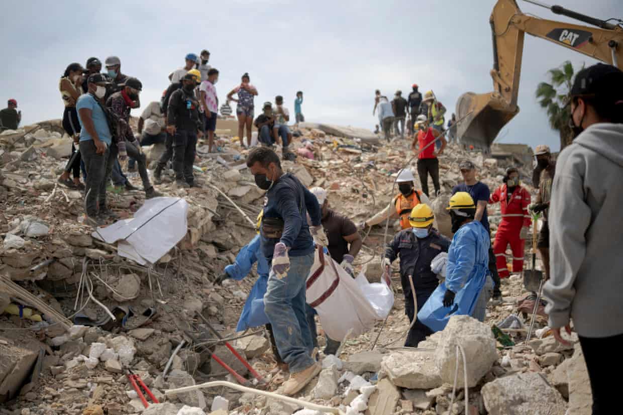 Volunteers remove a body from wreckage while others watch