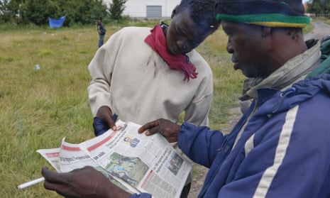 Migrants reading an article about David Cameron in a French local newspaper at the ‘Jungle’ migrant camp near Calais.