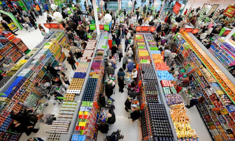 Shoppers crowd the aisles in a busy supermarket.