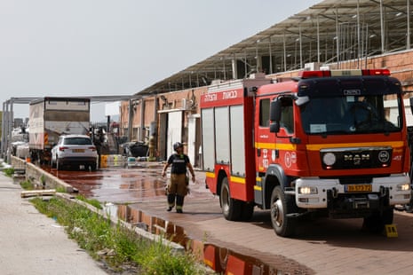 An Israeli firefighter walks towards a firetruck as they work on a factory building that hit was by a Hezbollah rocket in Kiryat Shmona in northern Israel near the Lebanon border, on Wednesday.