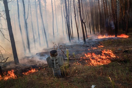 A rocket sticks out of the ground amid the flames of a forest fire