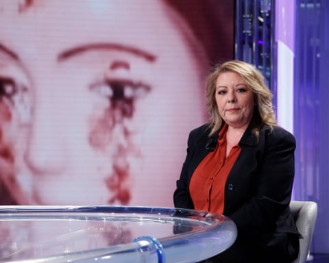 A woman pictured in a TV studio in front of a large image of a statue apparently shedding tears of blood