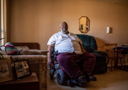 A man in a motorized wheelchair is shown in his home.