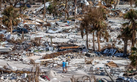 Two people walk among debris on an RV park in Fort Myers beach, Florida, US, in 2022 after Hurricane Ian swept across the area.