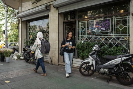 A woman walking out of a building holding a drink in a cup