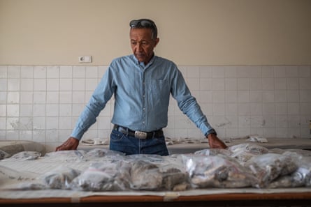 A man stands behind a worktop laid out with fossils in plastic bags