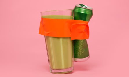 A can of beer taped to a glass of green juice