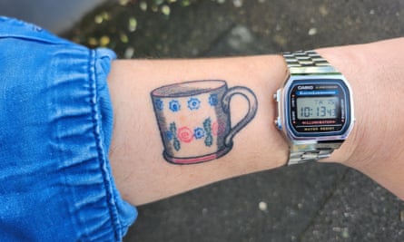 A tattoo of a mug on a forearm